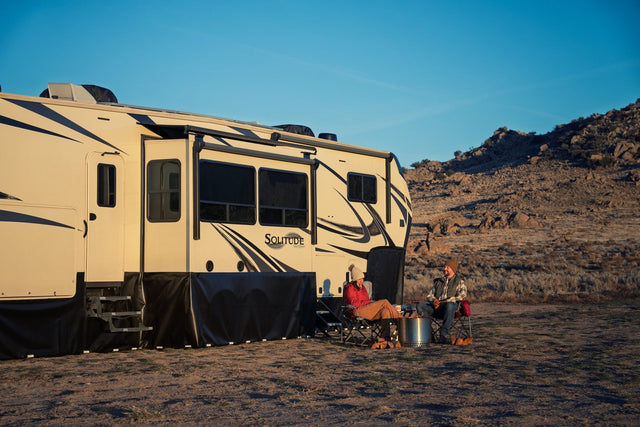 EZ Snap skirting panels enclosing the underbelly of a fifth wheel at golden hour, with owners seated outside