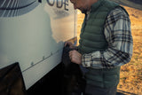 Snapping black EZ Snap skirting onto the studs along the side of an RV
